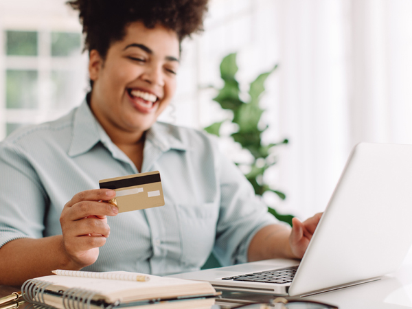 A woman smiling holding a debit card donating to SEBH
