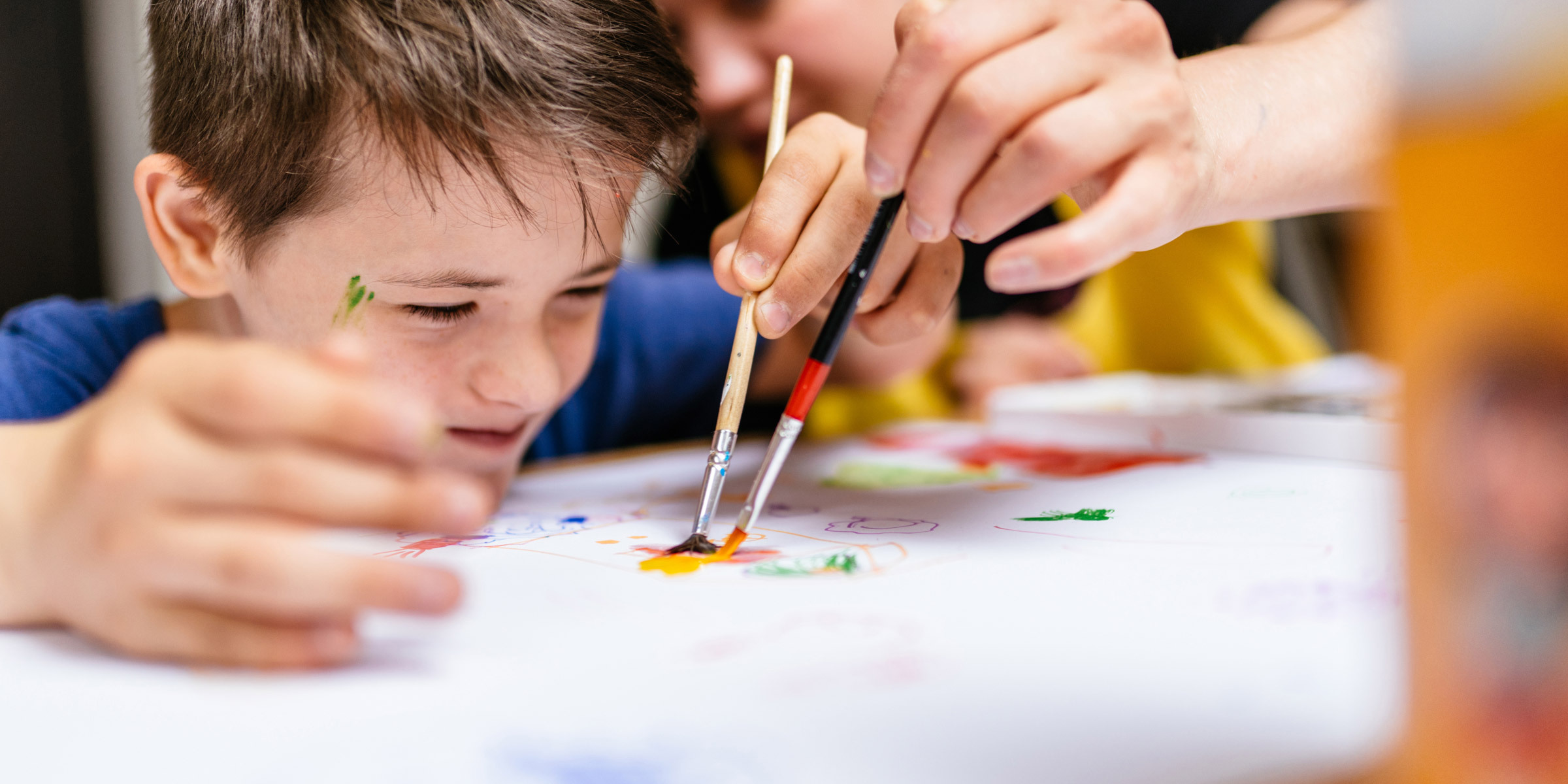 Young boy painting focused on painting on desk