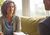 Middle-aged woman sitting on a couch smiling at a counselor