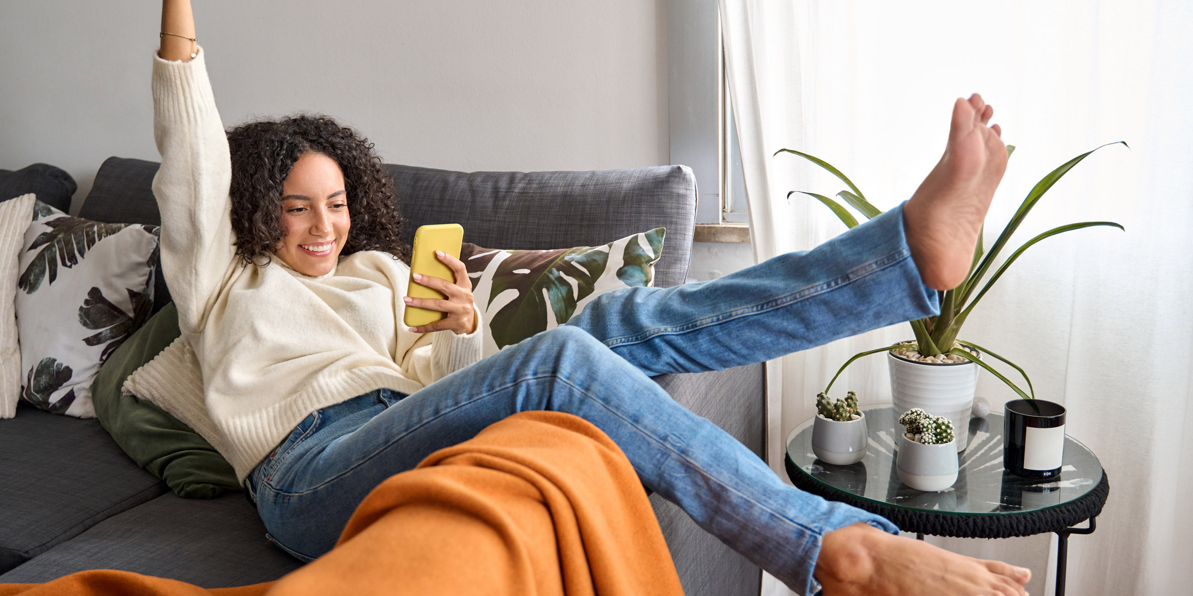 Woman getting excited looking at her smartphone with her arm up and kicking her legs