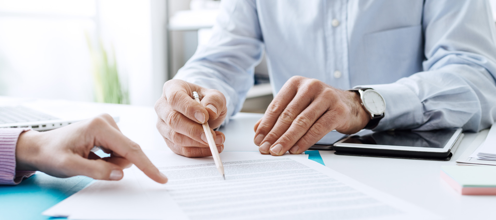 Two people signing a document at a desk.